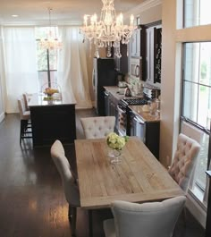 a dining room table with chairs and a chandelier hanging from it's ceiling