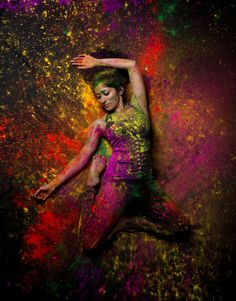 a woman with colorful paint all over her body and arms, posing for the camera