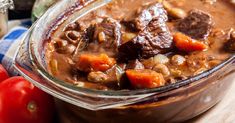 a glass bowl filled with beef stew next to a red pepper on a cutting board