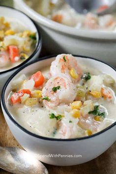 two bowls filled with shrimp and corn chowee on top of a wooden cutting board