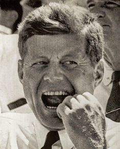 an old black and white photo of a man laughing with his hand on his mouth