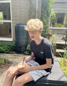 a young boy sitting on top of a black suitcase holding a pen and writing something