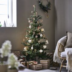 a small christmas tree in a living room next to a window with presents under it