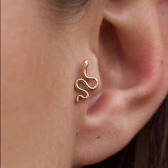 a woman wearing a gold earring with a snake design on the end of it