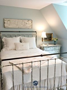 a bed with white sheets and pillows in a bedroom next to an attic dormer