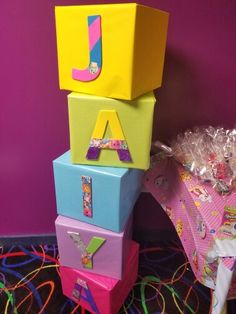 a stack of brightly colored blocks with the letter j on them, sitting in front of a purple wall