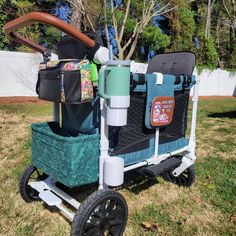 a stroller that is sitting in the grass with some bags on top of it