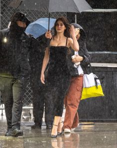 two women walking in the rain with an umbrella