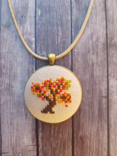 a cross stitch necklace with a tree on it