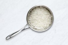 white rice in a silver pot on a marble surface