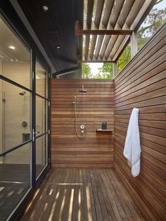 an outdoor shower with wooden flooring and walls