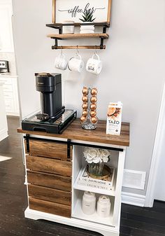 a coffee bar with wooden drawers and shelves on the wall, along with two mugs