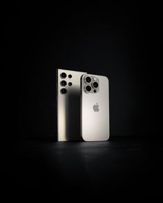 two silver and white iphones sitting side by side in the dark with their lids open