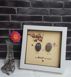 two rocks with eyes and flowers are in front of a frame that says, you rock my world