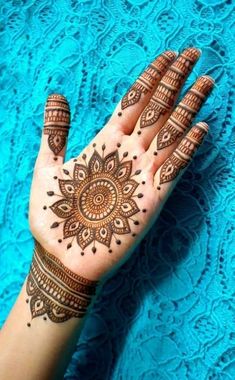 a woman's hand with henna tattoos on it and her hands in the shape of a flower