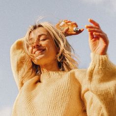 a woman in a yellow sweater is holding something up to her head