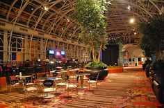 the inside of a restaurant with tables and chairs, plants on either side of them