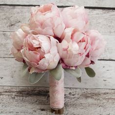 a bouquet of pink flowers sitting on top of a white wooden floor next to a wall