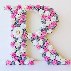 the letter k made out of flowers is displayed on a white surface with pink and black roses