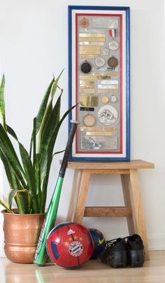 a wooden table with a potted plant next to it and an art piece hanging on the wall