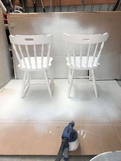 two white chairs sitting on top of a floor next to a bucket with a blow dryer