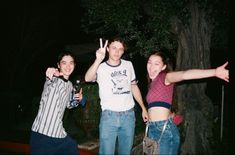 three people standing next to each other with their hands in the air and one person holding a beer