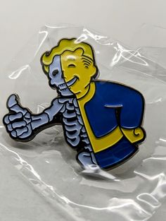 a yellow and blue pin with a cartoon character on it's back in a plastic bag