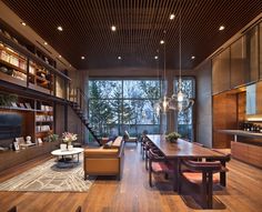 a living room filled with furniture and a large window next to a wooden floor covered in bookshelves