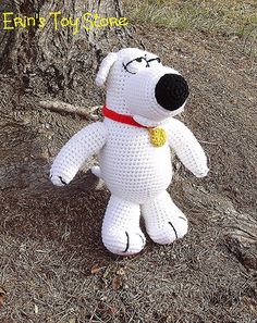 a white crocheted stuffed dog sitting on the ground next to a tree branch