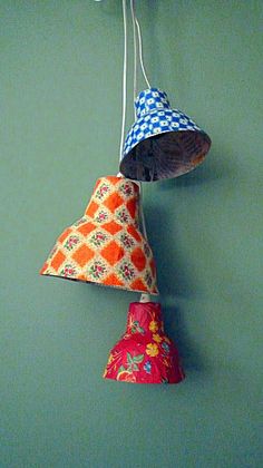 three colorful lamps hanging from a green wall