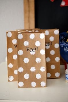 three brown paper bags with white polka dots on them sitting on a table next to other items