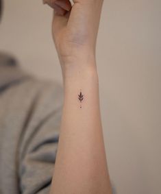 a woman's arm with a small tattoo on her left wrist that has a single leaf on it