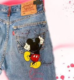 a pair of jean shorts with mickey mouse on it's back pocket and some paint splatters around the waist