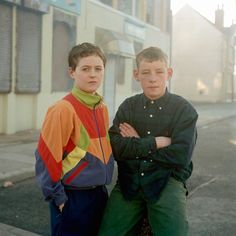 two boys standing next to each other on the street