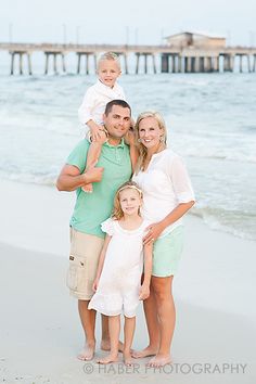 a family poses on the beach for a photo in front of the ocean and pier