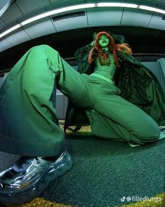 a woman dressed in green is sitting on the floor with her legs spread wide open