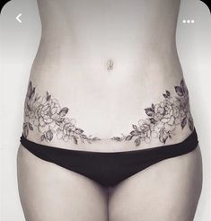 a woman's stomach with flowers and leaves on the side, as if it were tattooing