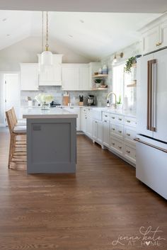 a large kitchen with white cabinets and wood flooring, an island in the middle