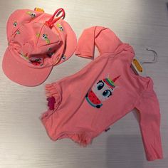 two pink onesuits and hat sitting on top of a table