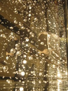 rain drops falling on the glass in front of a building with lights shining through it