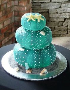 a three tiered green cake with white stars on it's top sitting on a black table