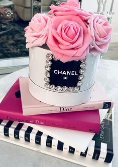 a stack of books with pink roses on top of them and a chanel bottle