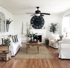 a living room filled with furniture and a clock mounted to the wall above it's fireplace