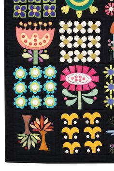 a black quilt with colorful flowers and plants on the front, along with other designs