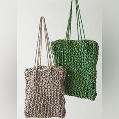 two knitted bags hanging from hooks on a white wall, one is green and the other is pink