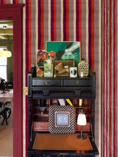 a room with striped wallpaper and an antique piano in the center, along with other furniture