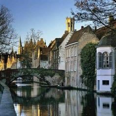 a river running through a small town next to tall buildings and a bridge over it