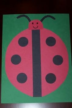 a ladybug painted on the side of a green and pink card with black dots