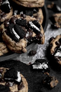 chocolate chip cookies with oreo chips and powdered sugar are on a table next to a knife