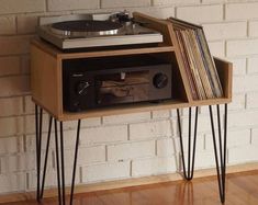 an old record player is sitting on top of a wooden table with hairpin legs